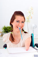 A girl using a pencil with her mouth.