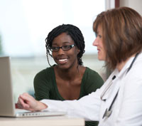 A doctor and teen looking at a computer screen.