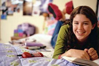 A girl laying on her bed reading a book.